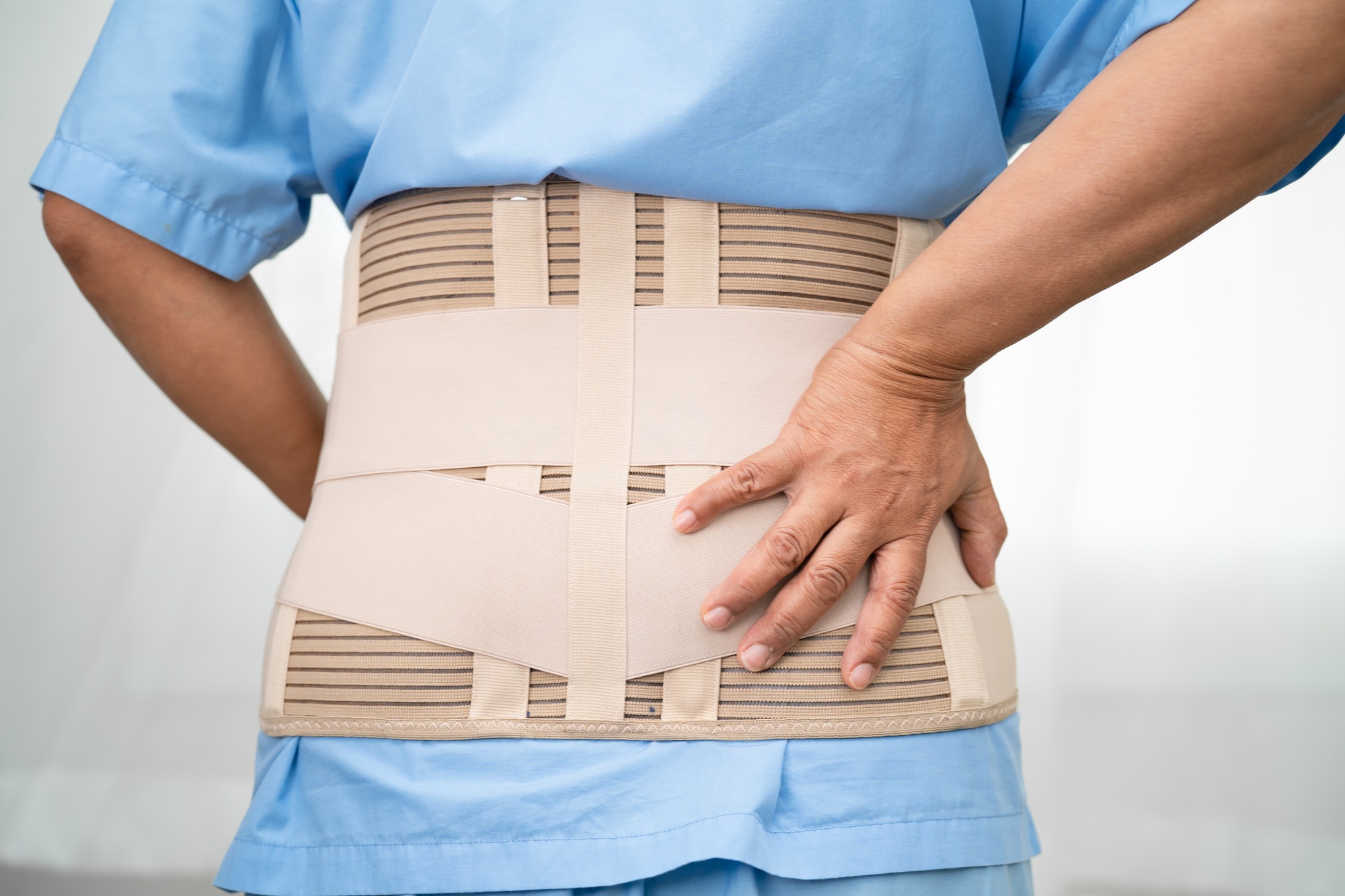 Asian lady patient wearing back pain support belt for orthopedic lumbar with walker.